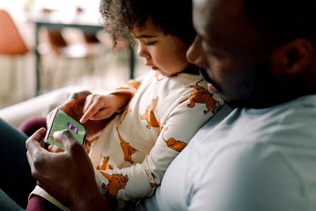 Father teaching daughter to play game on smart phone at home Sweden, Stockholm, model released, property released Copyright: xMaskotx , MA91865