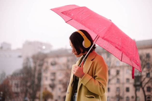 Thoughtful young woman in headphones holding umbrella walking in city CR_DMBE220203-885831-01 ,model released, Symbolfoto