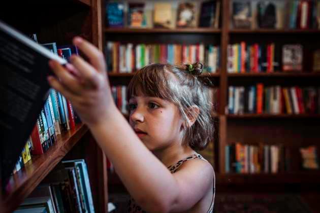 Child at library bookstore looking at books Bayfield, Wisconsin, United States CR_AZBI220202-914425-01 ,model released, Symbolfoto