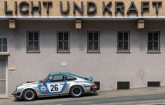 Licht und Kraft. Lichtreklame an einem Gewerbebau in Stuttgart. Davor ein Porsche. Stuttgart, Baden-Württemberg, Deutschland.