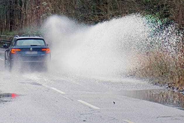 Gefährliche Straßenverhältnisse bei Starkregen Das Wasser von einer nach Starkregen überfluteten Straße wird von den Autos in die Luft gerissen und sorgt bei vielen Fahrern für Schrecksekunden. Essen Nordrhein-Westfalen Deutschland L191