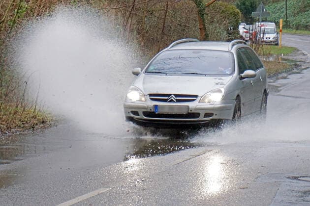 Gefährliche Straßenverhältnisse bei Starkregen Das Wasser von einer nach Starkregen überfluteten Straße wird von den Autos in die Luft gerissen und sorgt bei vielen Fahrern für Schrecksekunden. Essen Nordrhein-Westfalen Deutschland L191