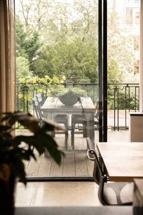 Wooden table and flower in light room near transparent door of terrace with wooden table and green plant near fence and trees in city, Property released CasaMedia_Keizersgracht371C_32.jpg Copyright: xCasaxMediax Model Released