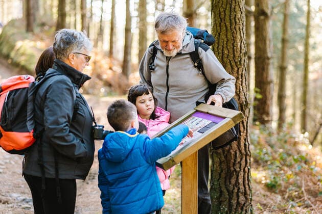 IMAGO Creative, Jahreszeit Herbst, Ferien Grandparents hikers with kids reading information on wooden board while standing on path in woods in autumn during trekking, Model released HodeiUnzueta_FamilyTrekking_7.jpg Copyright: xHodeixUnzuetax MR