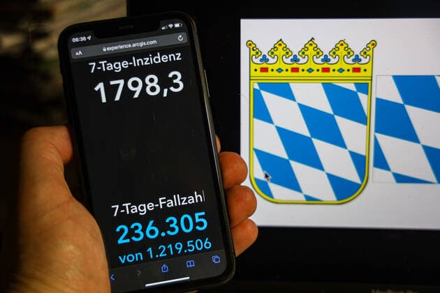 Coronavirus in Deutschland - Covid-19-Dashboard des Robert Koch-Institut DEU, Deutschland, Bayern 13.02.2022: Die 7-Tage-Inzidenz für das Bundesland (Fälle letzte 7 Tage 100.000 EW) wird auf einem iPhone angezeigt, im Hintergrund das Landeswappen