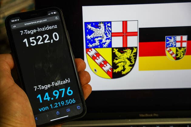 Coronavirus in Deutschland - Covid-19-Dashboard des Robert Koch-Institut DEU, Deutschland, Saarland 13.02.2022: Die 7-Tage-Inzidenz für das Bundesland (Fälle letzte 7 Tage 100.000 EW) wird auf einem iPhone angezeigt, im Hintergrund das Landeswappen