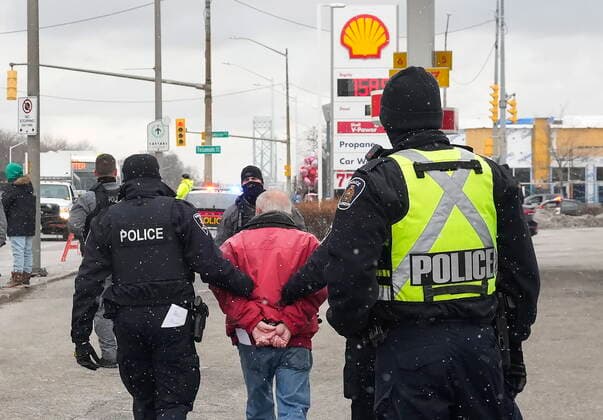 February 13, 2022, WINDSOR, ON, CANADA: A protester is arrested by as police remove truckers and supporters after a court injunction gave police the power to enforce the law after blocking the access leading from the Ambassador Bridge, linking Detroit and Windsor, as truckers and their supporters continue to protest against the COVID-19 vaccine mandates and restrictions in Windsor, Ont., on Sunday, February 13, 2022. WINDSOR CANADA - ZUMAc35_ 20220213_zaf_c35_063 Copyright: xNathanxDenettex