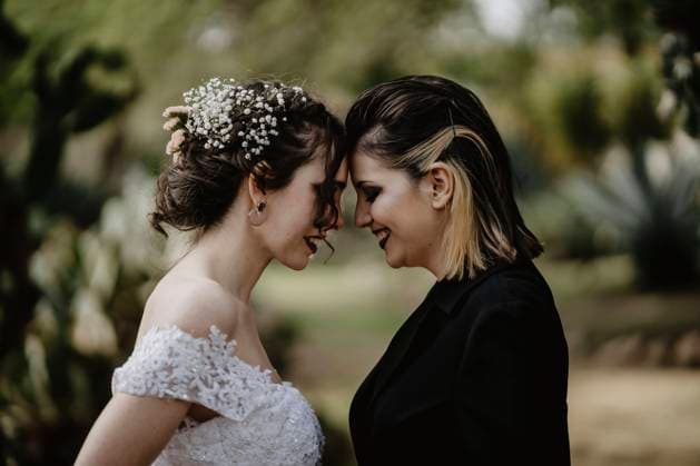 Side view of cheerful lesbian couple smiling and touching foreheads on wedding day on blurred background of park MiguelAngelJunquera_LGBTWedding_46.jpg Copyright: xMiguelxAngelxJunquerax Model Released
