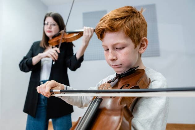 IMAGO Creative: Bildung, Musikerziehung Female teacher and boy playing violins during lesson in modern music school, Model released, Property released OlgaGuardon_MusicSchool_23.jpg Copyright: xOlgaxGuardonx MR