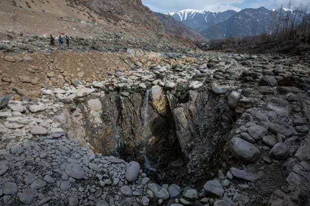 (220218) -- SRINAGAR, Feb. 18, 2022 -- People walk near a vertical sinkhole that has developed in the middle of a river bed at a village in Anantnag district, about 94 km south of Srinagar city, the summer capital of Indian-controlled Kashmir, Feb. 18, 2022. A vertical sinkhole that has developed in the middle of a river bed has devoured a freshwater stream in Indian-controlled Kashmir, officials said Thursday. The sinkhole has been draining in all the run of the stream water into it and left the downstream portion dry, killing trout fish in large numbers. It has also caused immeasurable damage to aquatic life. ) KASHMIR-SRINAGAR-VERTICAL SINKHOLE JavedxDar 