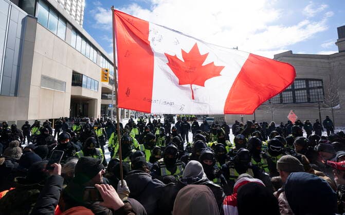 Kanada, Protest gegen Corona-Maßnahmen in Ottawa - Polizei beginnt mit Räumung von LKW-Blockade February 18, 2022, Ottawa, ON, Canada: A Canadian flag is held up by a protester as police move the line up as they work to end a protest, which started in opposition to mandatory COVID-19 vaccine mandates and grew into a broader anti-government demonstration and occupation, in Ottawa, Friday, Feb. 18, 2022. Ottawa Canada - ZUMAc35_ 20220218_zaf_c35_132 Copyright: xAdrianxWyldx
