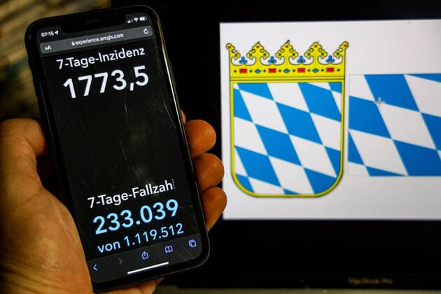 Coronavirus in Deutschland - Covid-19-Dashboard des Robert Koch-Institut DEU, Deutschland, Bayern 20.02.2022: Die 7-Tage-Inzidenz für das Bundesland (Fälle letzte 7 Tage 100.000 EW) wird auf einem iPhone angezeigt, im Hintergrund das Landeswappen