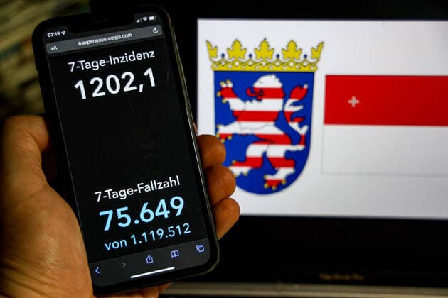 Coronavirus in Deutschland - Covid-19-Dashboard des Robert Koch-Institut DEU, Deutschland, Hessen 20.02.2022: Die 7-Tage-Inzidenz für das Bundesland (Fälle letzte 7 Tage 100.000 EW) wird auf einem iPhone angezeigt, im Hintergrund das Landeswappen