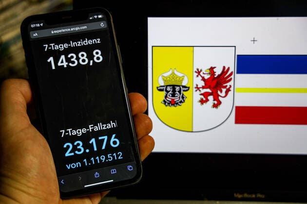 Coronavirus in Deutschland - Covid-19-Dashboard des Robert Koch-Institut DEU, Deutschland, Mecklenburg-Vorpommern 20.02.2022: Die 7-Tage-Inzidenz für das Bundesland (Fälle letzte 7 Tage 100.000 EW) wird auf einem iPhone angezeigt, im Hintergrund das Landeswappen