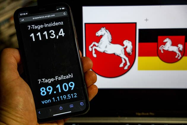 Coronavirus in Deutschland - Covid-19-Dashboard des Robert Koch-Institut DEU, Deutschland, Niedersachsen 20.02.2022: Die 7-Tage-Inzidenz für das Bundesland (Fälle letzte 7 Tage 100.000 EW) wird auf einem iPhone angezeigt, im Hintergrund das Landeswappen
