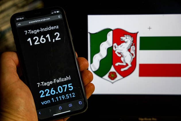 Coronavirus in Deutschland - Covid-19-Dashboard des Robert Koch-Institut DEU, Deutschland, Nordrhein-Westfalen 20.02.2022: Die 7-Tage-Inzidenz für das Bundesland (Fälle letzte 7 Tage 100.000 EW) wird auf einem iPhone angezeigt, im Hintergrund das Landeswappen