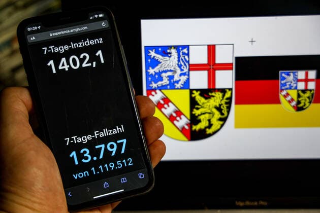 Coronavirus in Deutschland - Covid-19-Dashboard des Robert Koch-Institut DEU, Deutschland, Saarland 20.02.2022: Die 7-Tage-Inzidenz für das Bundesland (Fälle letzte 7 Tage 100.000 EW) wird auf einem iPhone angezeigt, im Hintergrund das Landeswappen