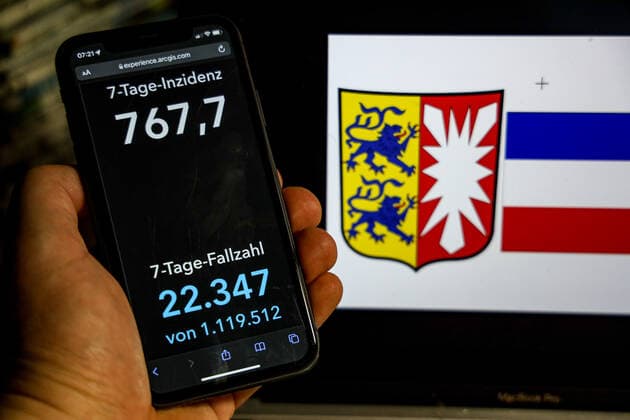 Coronavirus in Deutschland - Covid-19-Dashboard des Robert Koch-Institut DEU, Deutschland, Schleswig-Holstein 20.02.2022: Die 7-Tage-Inzidenz für das Bundesland (Fälle letzte 7 Tage 100.000 EW) wird auf einem iPhone angezeigt, im Hintergrund das Landeswappen