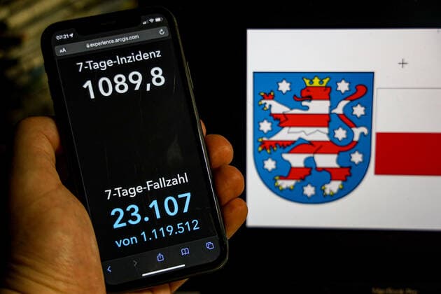 Coronavirus in Deutschland - Covid-19-Dashboard des Robert Koch-Institut DEU, Deutschland, Thüringen 20.02.2022: Die 7-Tage-Inzidenz für das Bundesland (Fälle letzte 7 Tage 100.000 EW) wird auf einem iPhone angezeigt, im Hintergrund das Landeswappen