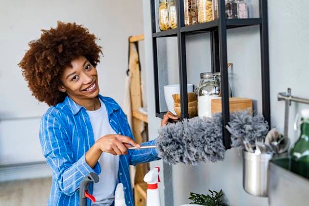 Smiling young Afro woman cleaning rack in kitchen at home model released property released, GIOF14737