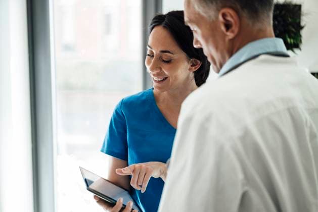Smiling nurse discussing with doctor over tablet PC in hospital model released property released, JOSEF06518