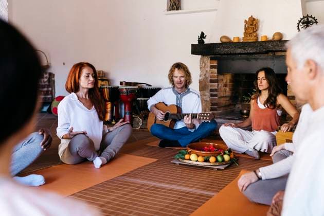 Musician playing guitar amidst friends meditating in farmhouse model released property released, JRFF05293