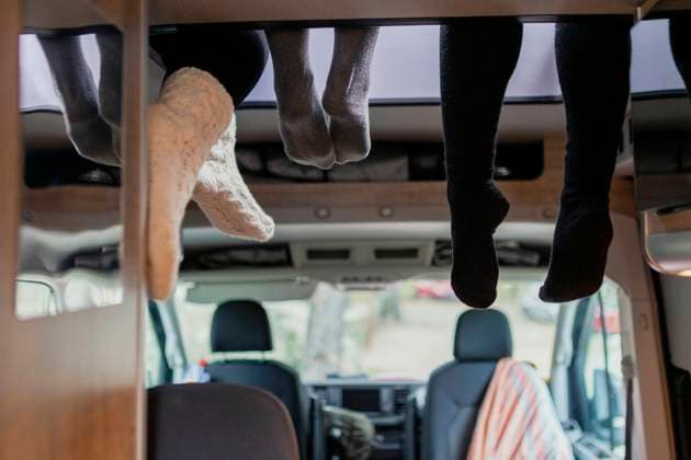 IMAGO Creative: Herbst, Touren mit dem Camper Friends wearing socks hanging legs in motor home model released, MRRF01852