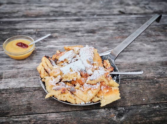 Kaiserschmarren served in cooking pan by apple sauce on wooden table, DIKF00614