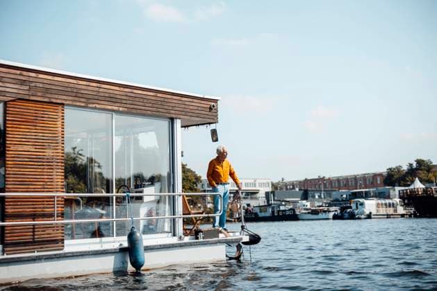 Senior man standing by railing at houseboat on sunny day model released property released, GUSF06891