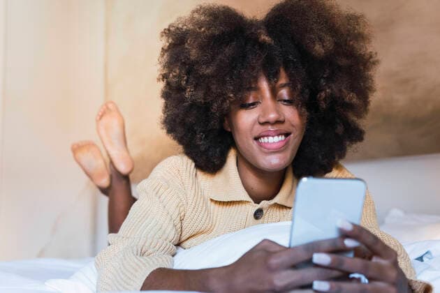 IMAGO Creative: Digitale Welt, Social Commerce Young woman using smart phone lying on bed at home model released property released, PNAF03112