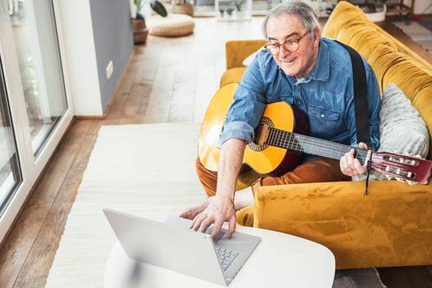 Senior man with guitar watching online tutorial on laptop in living room model released property released, UUF25348