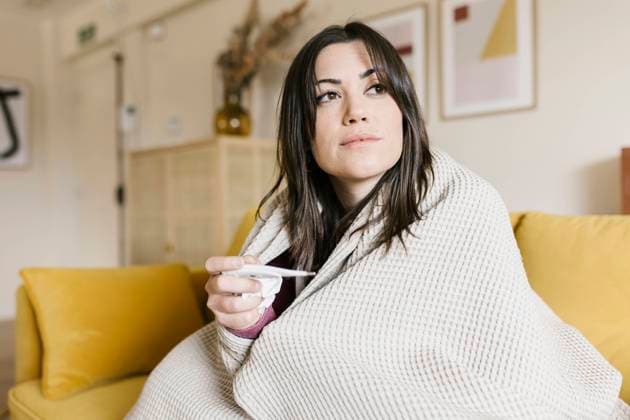 Beautiful woman wrapped in blanket holding thermometer in living room model released property released, XLGF02624