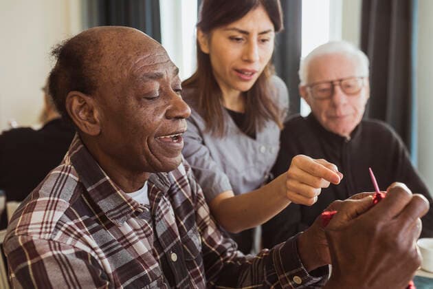 Female caregiver teaching senior man knitting in nursing home Sweden, Stockholm, model released, property released Copyright: xMaskotx , MA92184