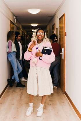 IMAGO Creative: 2022 Favoriten Happy young woman with diary while multiracial friends in background at corridor in dorm Sweden, Stockholm, model released, property released Copyright: xMaskotx , MA92268