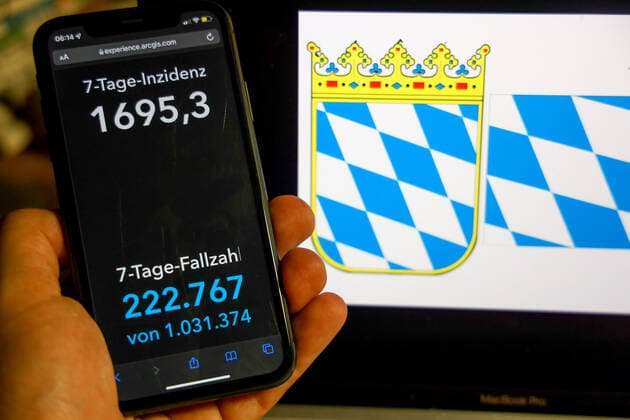 Coronavirus in Deutschland - Covid-19-Dashboard des Robert Koch-Institut DEU, Deutschland, Bayern 27.02.2022: Die 7-Tage-Inzidenz für das Bundesland (Fälle letzte 7 Tage 100.000 EW) wird auf einem iPhone angezeigt, im Hintergrund das Landeswappen