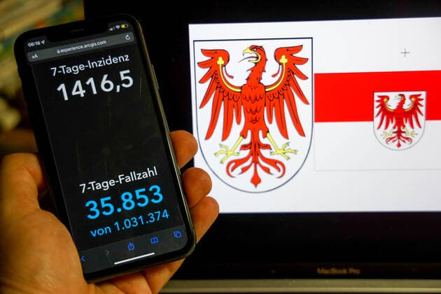 Coronavirus in Deutschland - Covid-19-Dashboard des Robert Koch-Institut DEU, Deutschland, Brandenburg 27.02.2022: Die 7-Tage-Inzidenz für das Bundesland (Fälle letzte 7 Tage 100.000 EW) wird auf einem iPhone angezeigt, im Hintergrund das Landeswappen