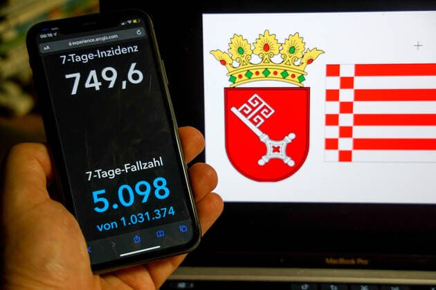 Coronavirus in Deutschland - Covid-19-Dashboard des Robert Koch-Institut DEU, Deutschland, Bremen 27.02.2022: Die 7-Tage-Inzidenz für das Bundesland (Fälle letzte 7 Tage 100.000 EW) wird auf einem iPhone angezeigt, im Hintergrund das Landeswappen