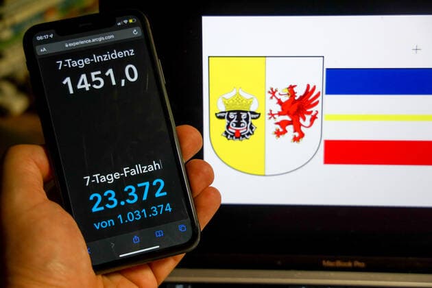 Coronavirus in Deutschland - Covid-19-Dashboard des Robert Koch-Institut DEU, Deutschland, Mecklenburg-Vorpommern 27.02.2022: Die 7-Tage-Inzidenz für das Bundesland (Fälle letzte 7 Tage 100.000 EW) wird auf einem iPhone angezeigt, im Hintergrund das Landeswappen