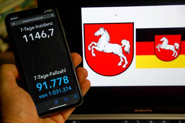 Coronavirus in Deutschland - Covid-19-Dashboard des Robert Koch-Institut DEU, Deutschland, Niedersachsen 27.02.2022: Die 7-Tage-Inzidenz für das Bundesland (Fälle letzte 7 Tage 100.000 EW) wird auf einem iPhone angezeigt, im Hintergrund das Landeswappen