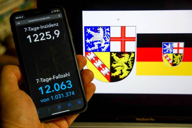 Coronavirus in Deutschland - Covid-19-Dashboard des Robert Koch-Institut DEU, Deutschland, Saarland 27.02.2022: Die 7-Tage-Inzidenz für das Bundesland (Fälle letzte 7 Tage 100.000 EW) wird auf einem iPhone angezeigt, im Hintergrund das Landeswappen