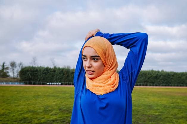 IMAGO Creative: Sport in der Stadt Muslim woman doing overhead tricep stretch on sports field Vilafranca del Penedès, Catalonia, Spain CR_SZPTRN220227-935150-01 ,model released, Symbolfoto