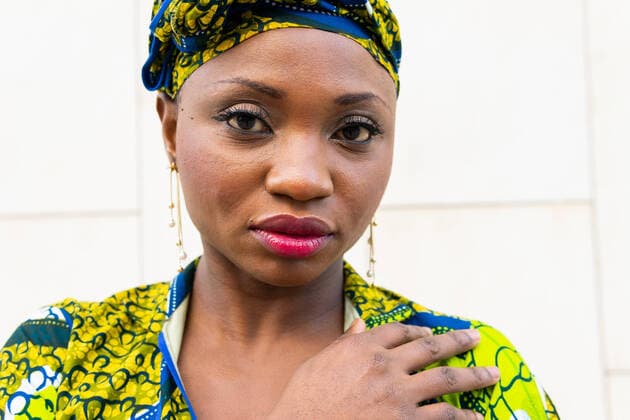 IMAGO Creative: Kollidierende Kulturen Dreamy elegant African female model in traditional turban and dress looking at camera thoughtfully while standing near white wall on street DavidMunoz_MarinaAfrican_5.jpg Copyright: xDavidxMunozx Model Released
