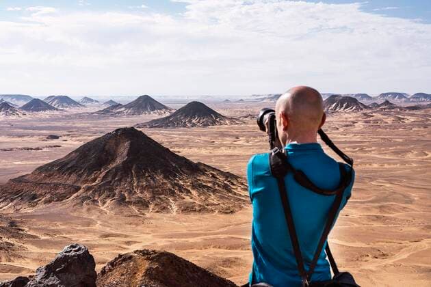IMAGO Creative: Welttourismustag am 27. September Back view of unrecognizable male photographer taking picture on professional photo camera of mounds located in black desert during trip in Egypt, Model released JavierBallester_Egypt_64.jpg Copyright: xJavierxBallesterx MR
