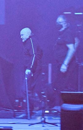 10.03.22, Hannover, Genesis Phil Collins betritt sehr krank und geschwächt die Bühne im Dunkeln mit Gehstock ZAG Arena in Hannover auf dem Expo Gelände :