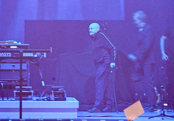 10.03.22, Hannover, Genesis Phil Collins betritt sehr krank und geschwächt die Bühne im Dunkeln mit Gehstock ZAG Arena in Hannover auf dem Expo Gelände :