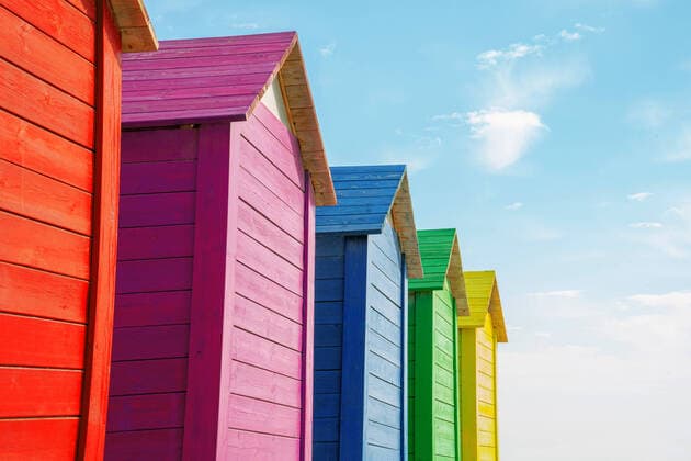 Creative Highlights Symbolbilder Various wooden multicolored toilet with triangular roofs placed in row against blue sky with clouds on summer day on beach DanielPerezLozao_ColorHouses_1.jpg Copyright: xDanielxPerezxLozaox Model Released