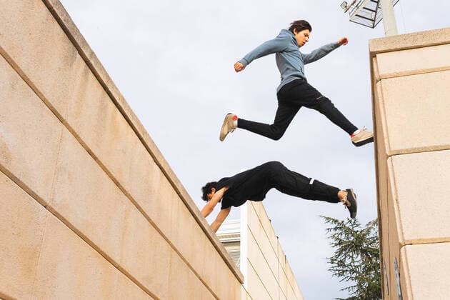 IMAGO Creative: 2022 Sport Favoriten Creative Highlights Symbolbilder From below side view of full length active men jumping over border roof while training in urban street DavidMunoz_ParkourMontjuic_7.jpg Copyright: xDavidxMunozx Model Released