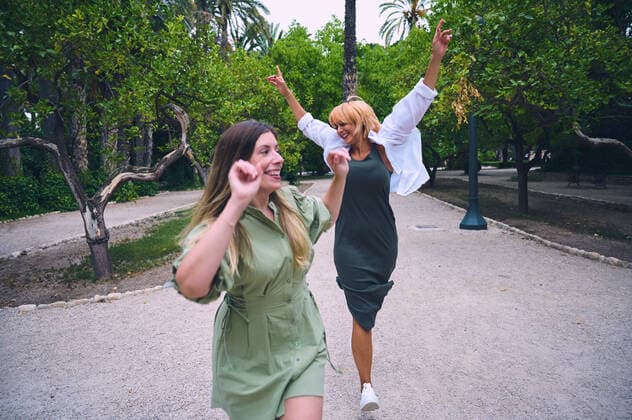 IMAGO Creative: Sommer, Sommertage im Stadtpark Delighted female friends walking together on path while having fun in park with green trees on summer day in city, Model released GermanLinares_OfficeWomen_23.jpg Copyright: xGermanxLinaresx MR