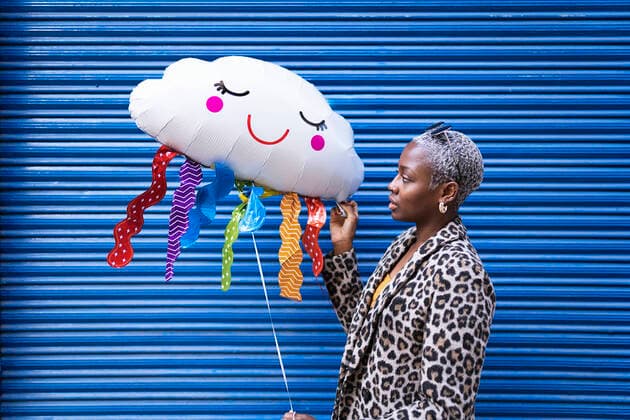 Creative Highlights Symbolbilder Side view of African American female with short hair in stylish wear standing on blue background with raining cloud balloon JavierBallester_LouiseBaloons_45.jpg Copyright: xJavierxBallesterx Model Released