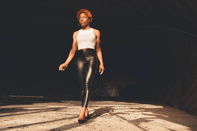 Creative Highlights Symbolbilder Full body of confident African American female in trendy outfit and high heels standing in dark tunnel with bright sunlight OscardeDios_LifestyleWithSilvia_9.jpg Copyright: xOscarxDexDiosx Model Released